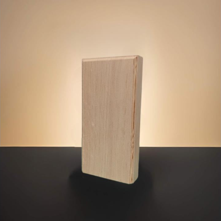 A rectangular block of mahogany natural wood standing upright on a dark surface against a warm beige background.