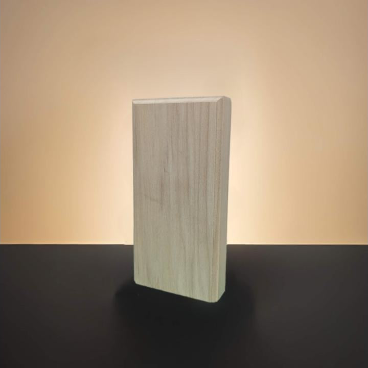 A rectangular poplar wood block with visible grain, standing upright on a dark surface against a warm beige gradient background.